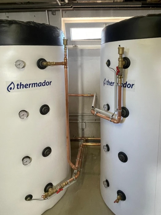 Deux ballons de stockage d'eau chaude sanitaire **Thermador** à isolation thermique noire, installés en local technique