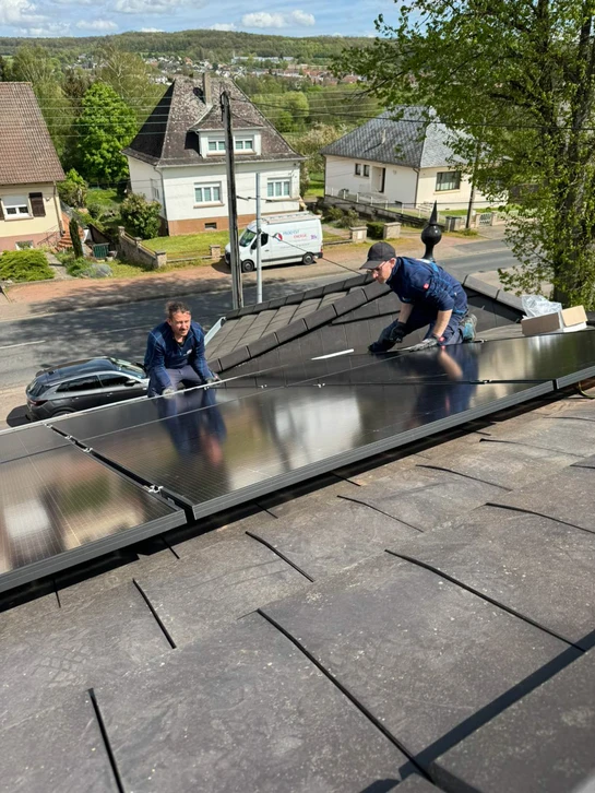 Maison individuelle moderne avec panneaux solaires photovoltaïques installés sur toiture à tuiles grises