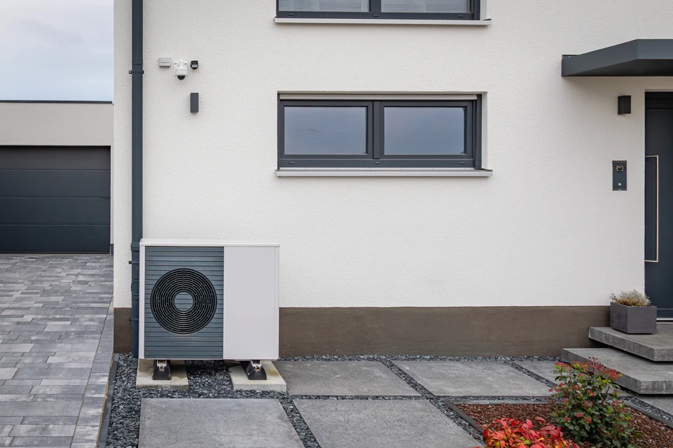Extérieur résidentiel moderne avec pompe à chaleur air-eau installée sur terrasse béton