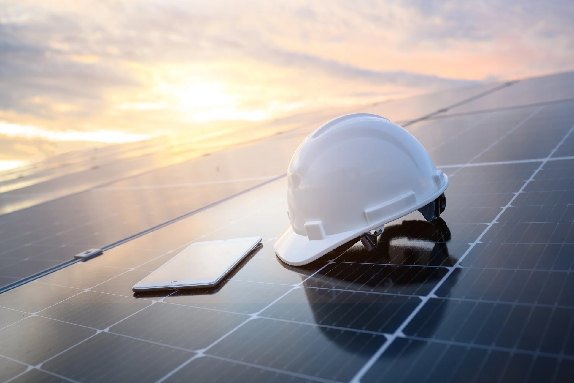 Technicien en équipement de protection individuelle installant des panneaux solaires photovoltaïques sur toiture résidentielle par temps ensoleillé